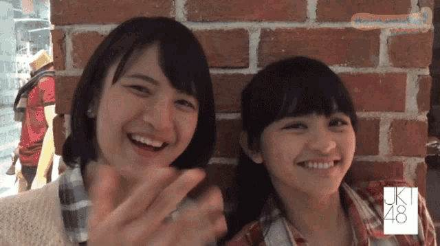 two girls standing next to each other with jk48 written on their shirts