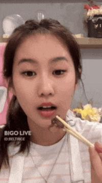 a girl is eating something with chopsticks and the word bigo live is on the bottom right