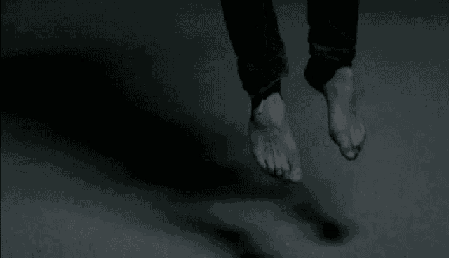a person 's feet are hanging from a string in the dark .