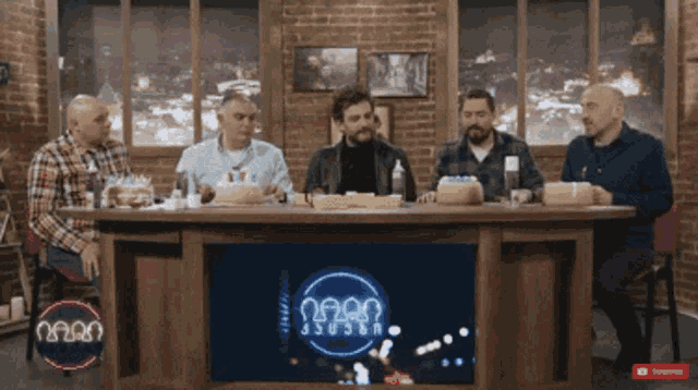 a group of men are sitting at a table with a sign that says ' n2n2n ' on it