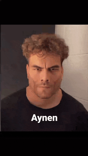 a man with curly hair and a beard is making a funny face with the word aynen on his face .