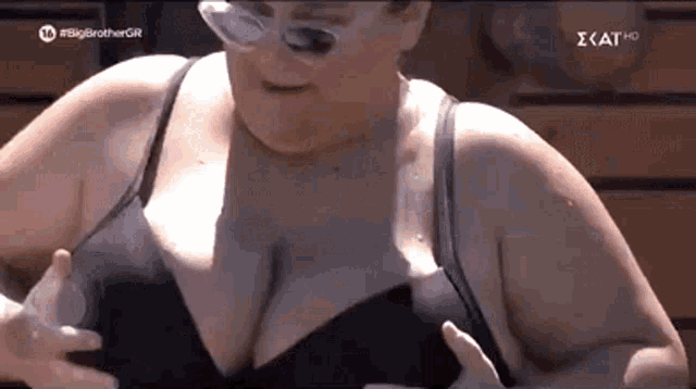 a woman in a black bra is holding her breasts while wearing sunglasses .