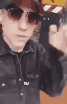 a young man wearing sunglasses and a hat is holding a gun .