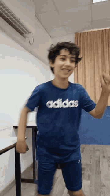 a young boy wearing an adidas shirt is dancing
