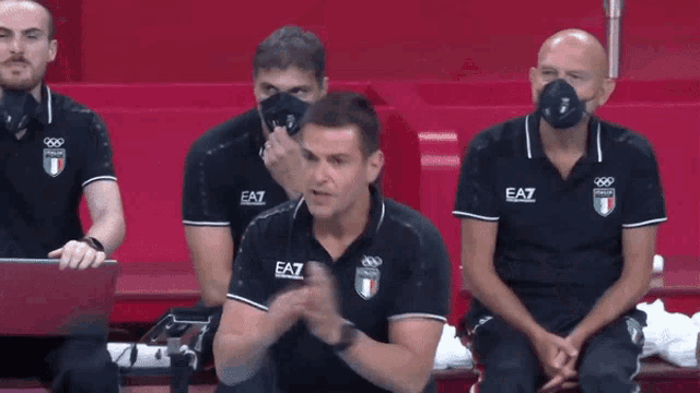 a group of men wearing ea7 polo shirts are sitting on a bench