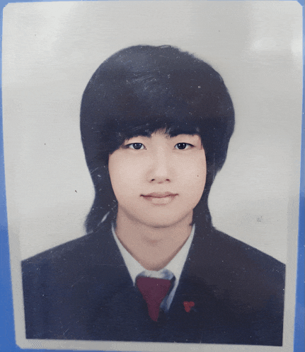 a young man with long black hair is wearing a black suit and red tie