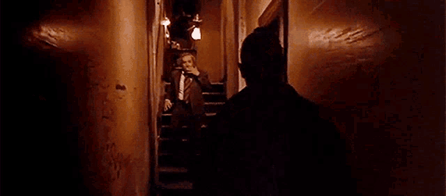 two men are standing next to each other in a dark hallway .