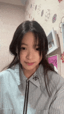 a girl wearing a striped shirt with a zipper on the front looks at the camera