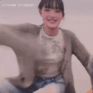 a woman wearing a cardigan and a tank top is dancing on a couch .