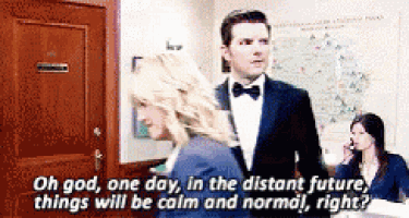 a man in a tuxedo and bow tie is talking to a woman in a blue jacket