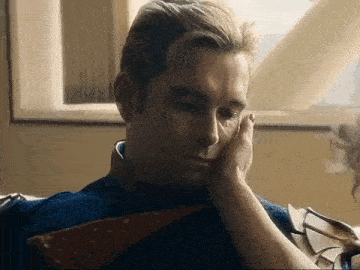 a man is laying on a couch with his hand on his face .