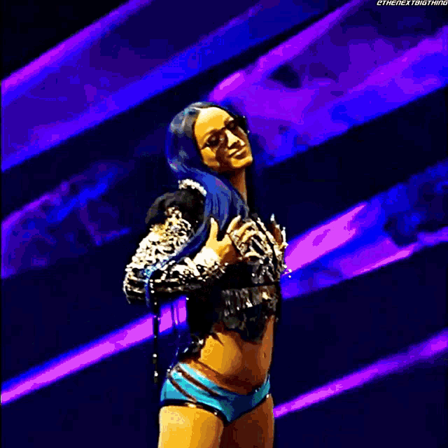 a female wrestler with blue hair is standing on a stage .