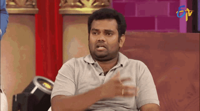 a man in a gray shirt is sitting in front of a tv screen that says tnt