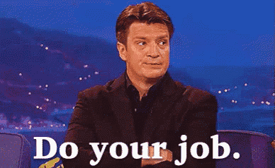 a man in a suit says " do your job " while sitting in a chair