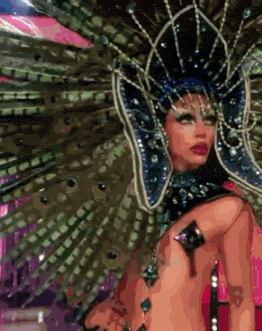 a naked woman is wearing a peacock costume with feathers and rhinestones .