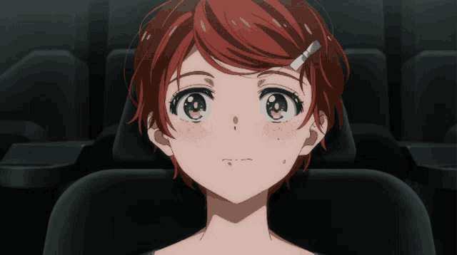 a girl with red hair and green eyes sitting in a dark room