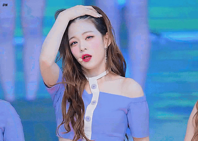 a woman in a purple off the shoulder top is holding her hand to her head