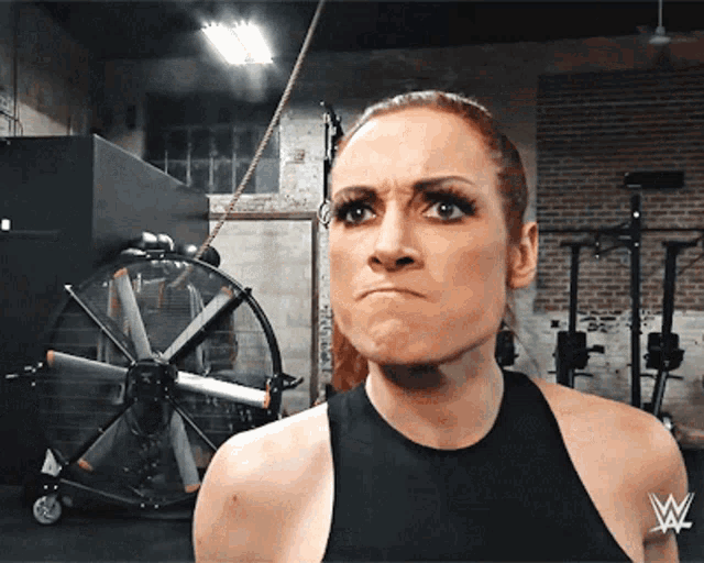 a woman with a wrestling logo on her arm makes a face