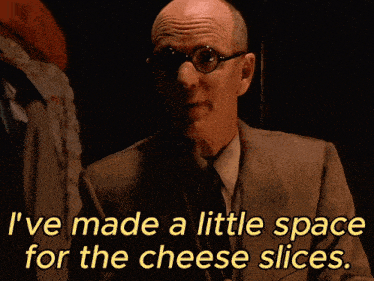 a man with glasses and a suit says " i ve made a little space for the cheese slices "