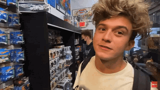 a young man standing in front of a shelf of hot wheels