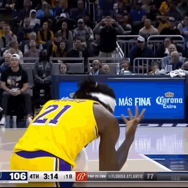 a basketball player wearing a yellow jersey with the number 21