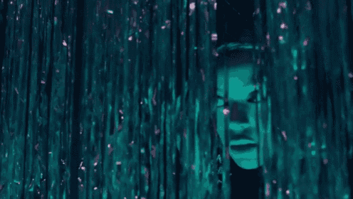 a close up of a person 's face behind a curtain of tinsel .
