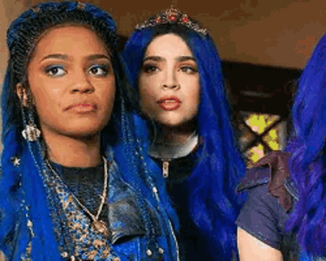 two women with blue hair and a tiara are standing next to each other in a room .
