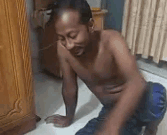 a shirtless man is kneeling down on the floor in a room .