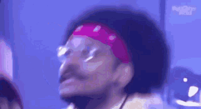 a man wearing glasses and a bandana is dancing in a club .