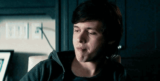 a young man is sitting in a chair with his eyes closed and making a funny face .