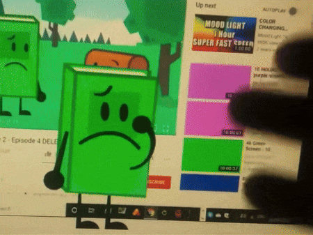 a green book with a sad face is standing in front of a computer screen that says up next