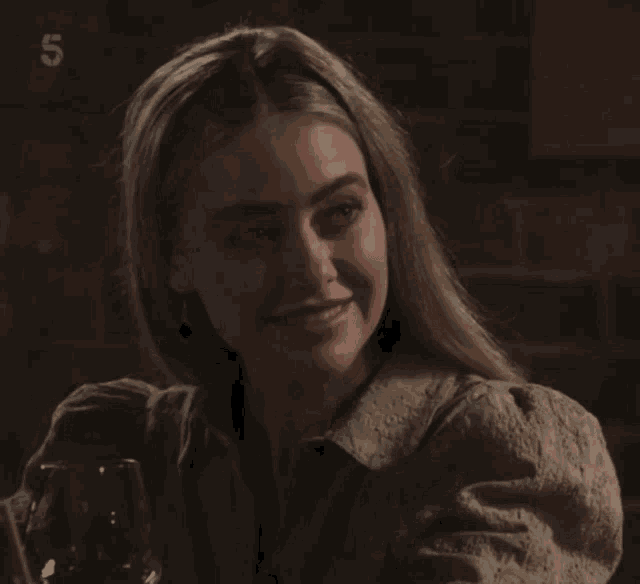 a woman is smiling and holding a glass of wine with the number 5 on the bottom right