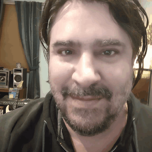 a man with a beard is smiling in front of a stereo system