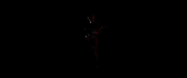 a man is playing an electric guitar in a dark room with red lights .