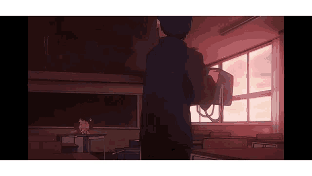 a man is standing in an empty classroom holding a bag .