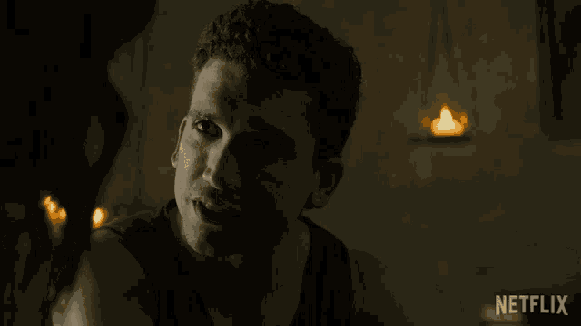 a man is smiling in a dark room with a netflix logo behind him