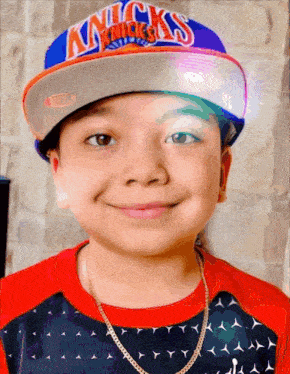 a young boy wearing a new york knicks hat smiles for the camera