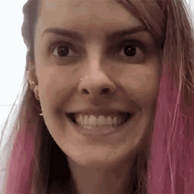 a close up of a woman 's face with pink hair and a nose ring .