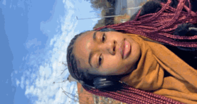 a woman wearing headphones and a scarf is smiling