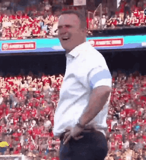 a man is standing in front of a crowd of people in a stadium .