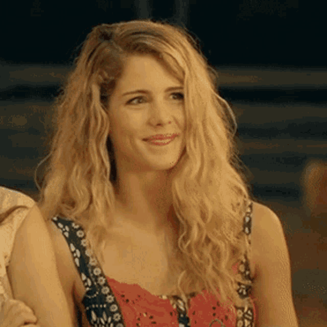 a woman with blonde hair is smiling and wearing a red tank top