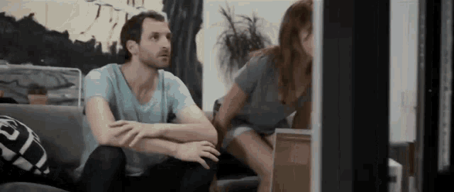 a man and woman are sitting on a couch looking at a laptop computer .
