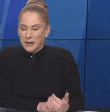 a woman in a black sweater is smiling while sitting at a desk .