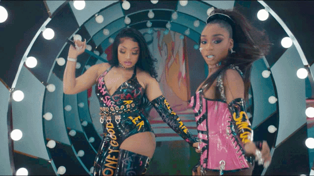 two women are dancing in a circle and one of their outfits says " oney good "