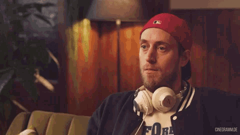 a man wearing headphones and a red hat is sitting on a green couch