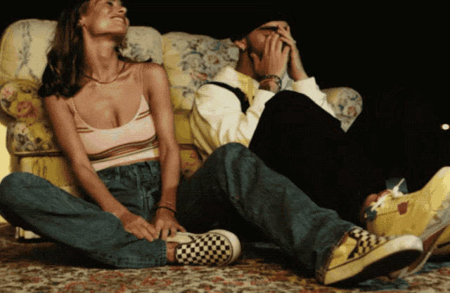 a man and a woman are sitting on a couch laughing