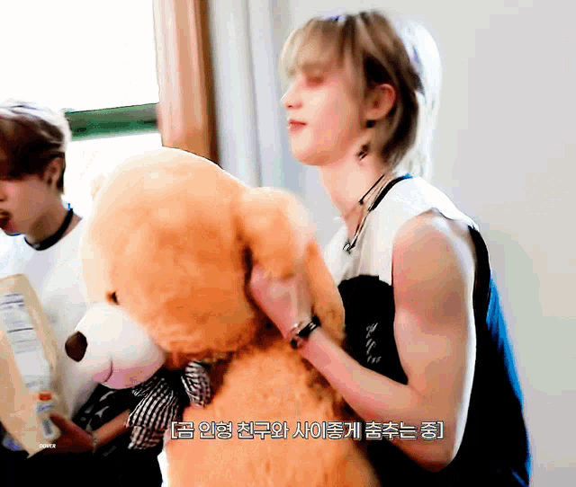 a man is holding a teddy bear with korean writing on the bottom