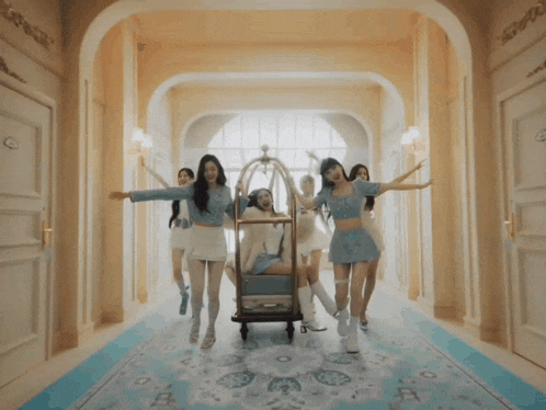 a group of women are standing in a hallway with a luggage cart