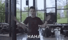 a young man is standing in a room with his arms outstretched and laughing .