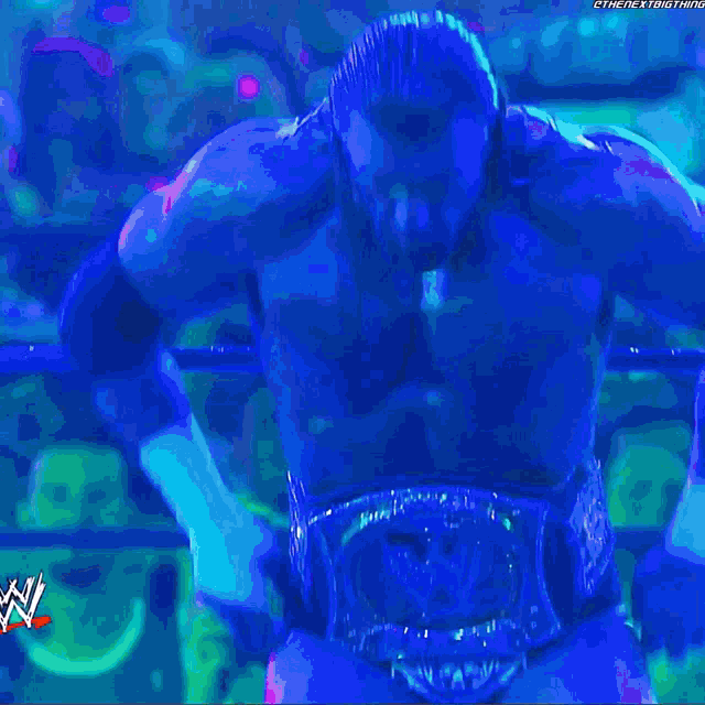 a shirtless wrestler is screaming in the rain with the letters w on the bottom right